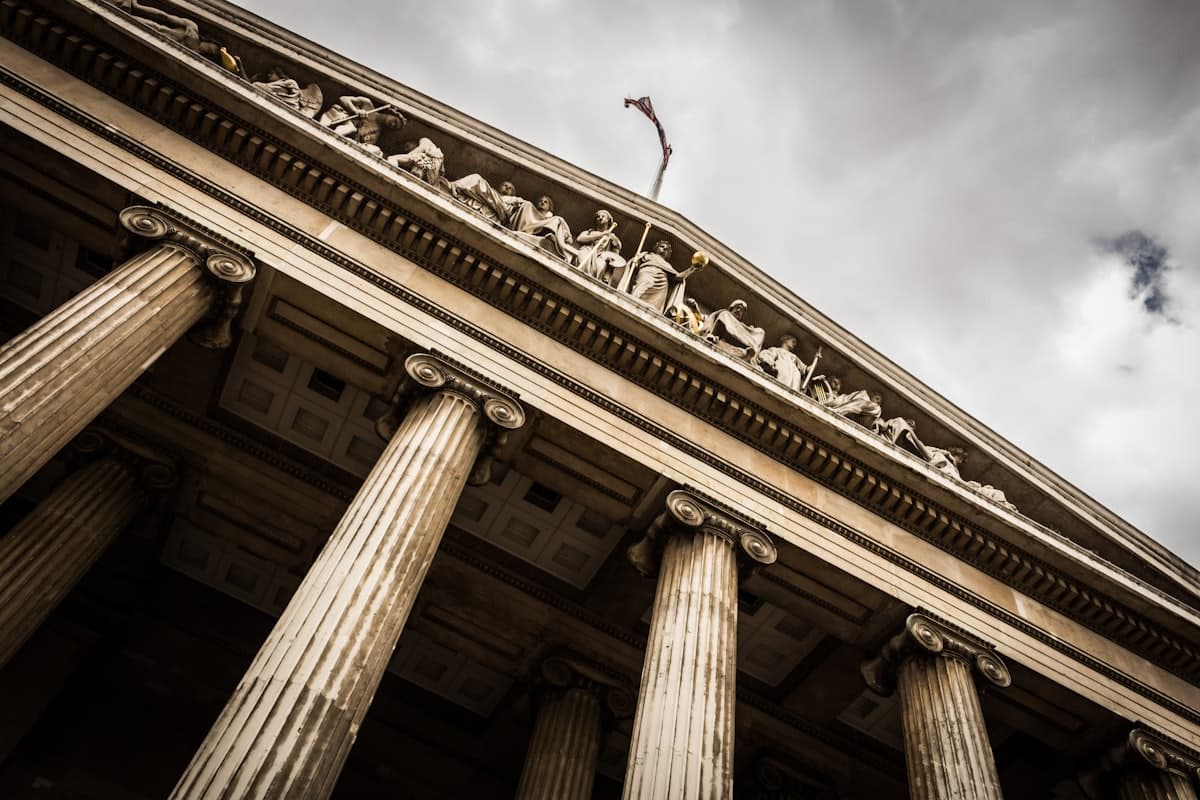 Neoclassical courthouse columns under a dramatic sky, representing criminal defense